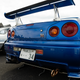 a close-up shot of the rear of an R34 nissan gt-r in blue, with a high wing on the trunk lid